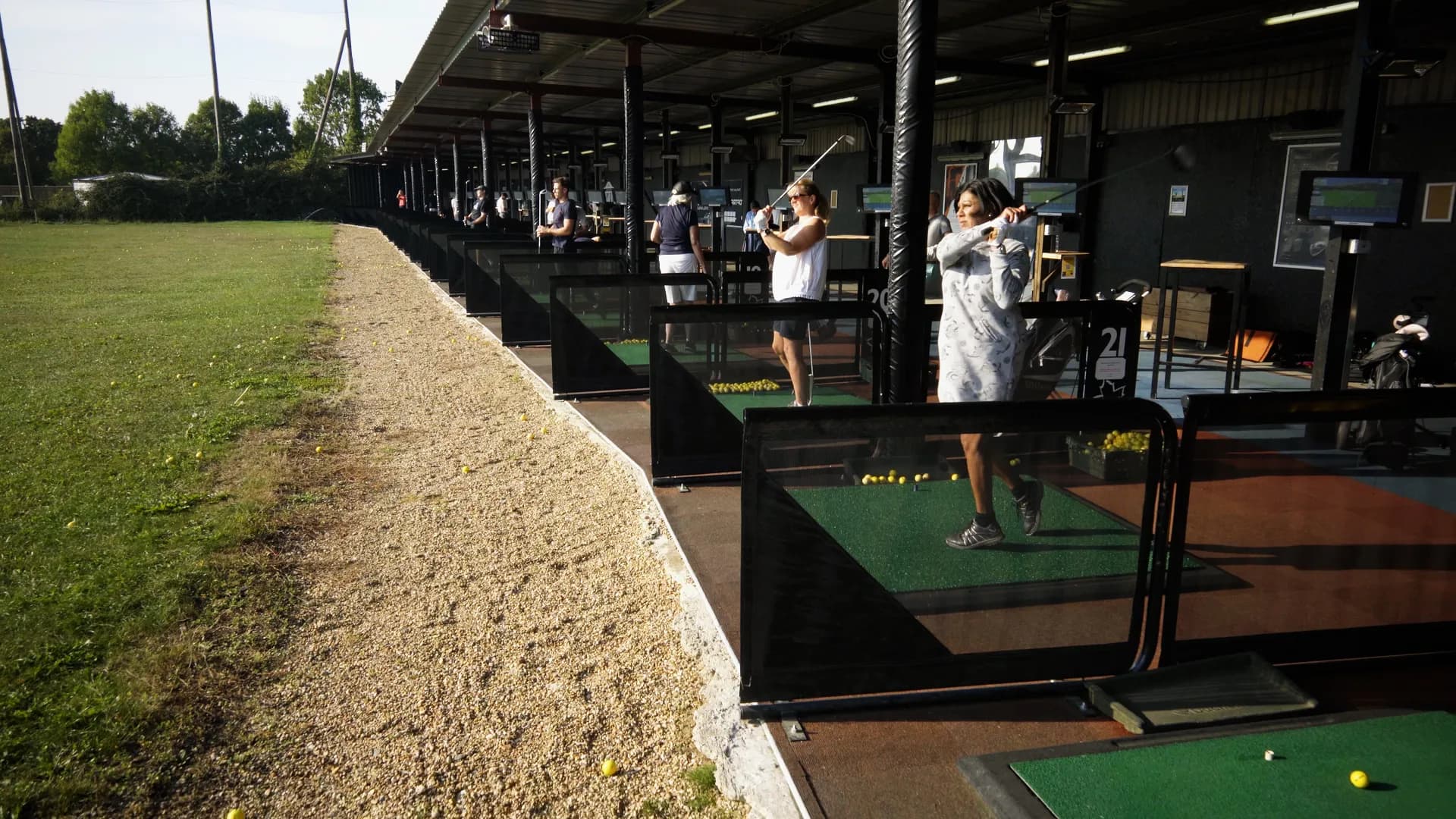 Golfers practising from adjacent driving-range bays at Horton Golf Park.