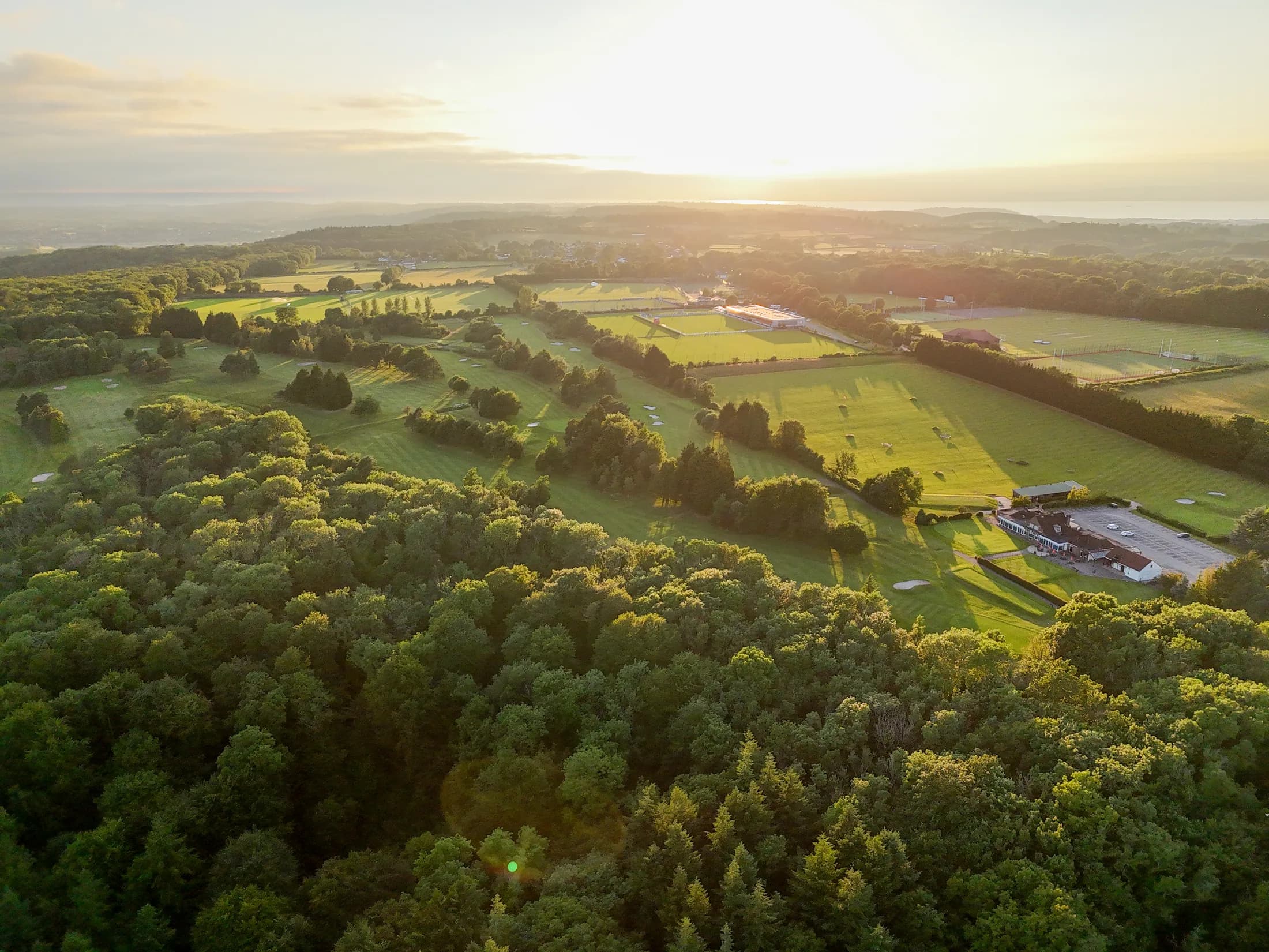 A high aerial view across Long Ashton Golf Club and the surrounding Bristol landscape at sunset.
