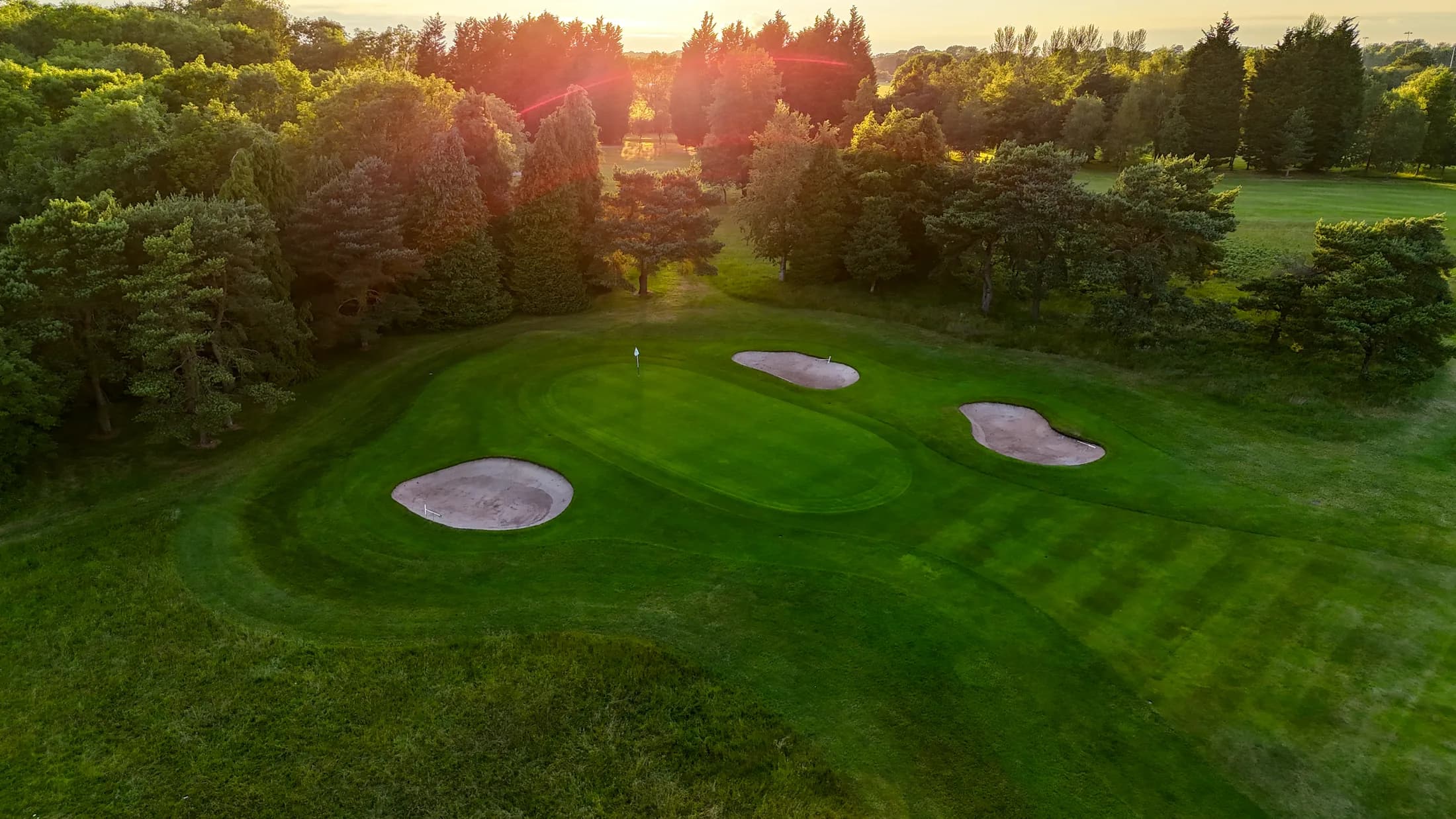 A sunset aerial view across a green and bunkers at Long Ashton Golf Club from the original project photography.
