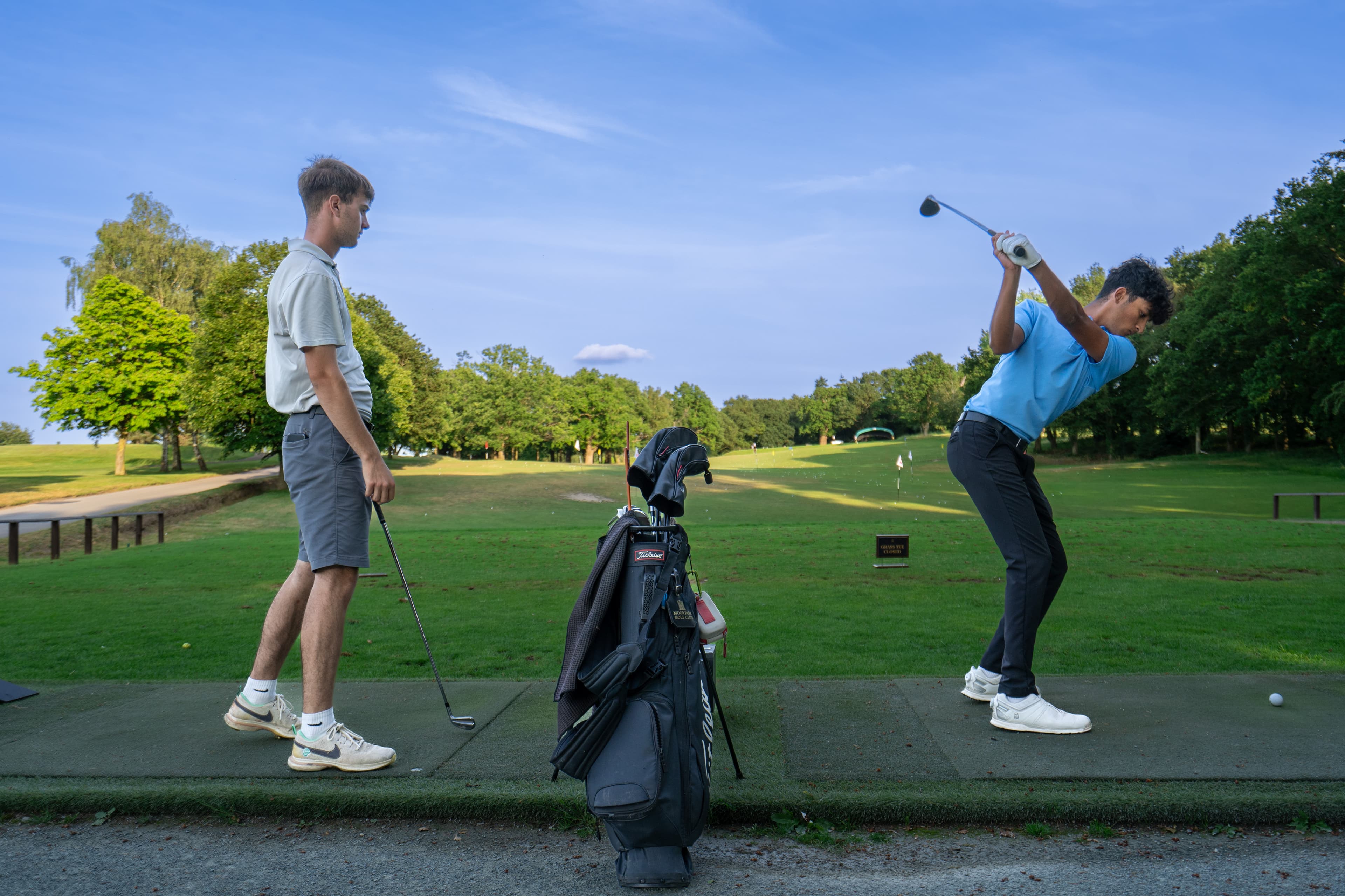 Two golfers on the practice ground at Moor Park, one mid-swing.