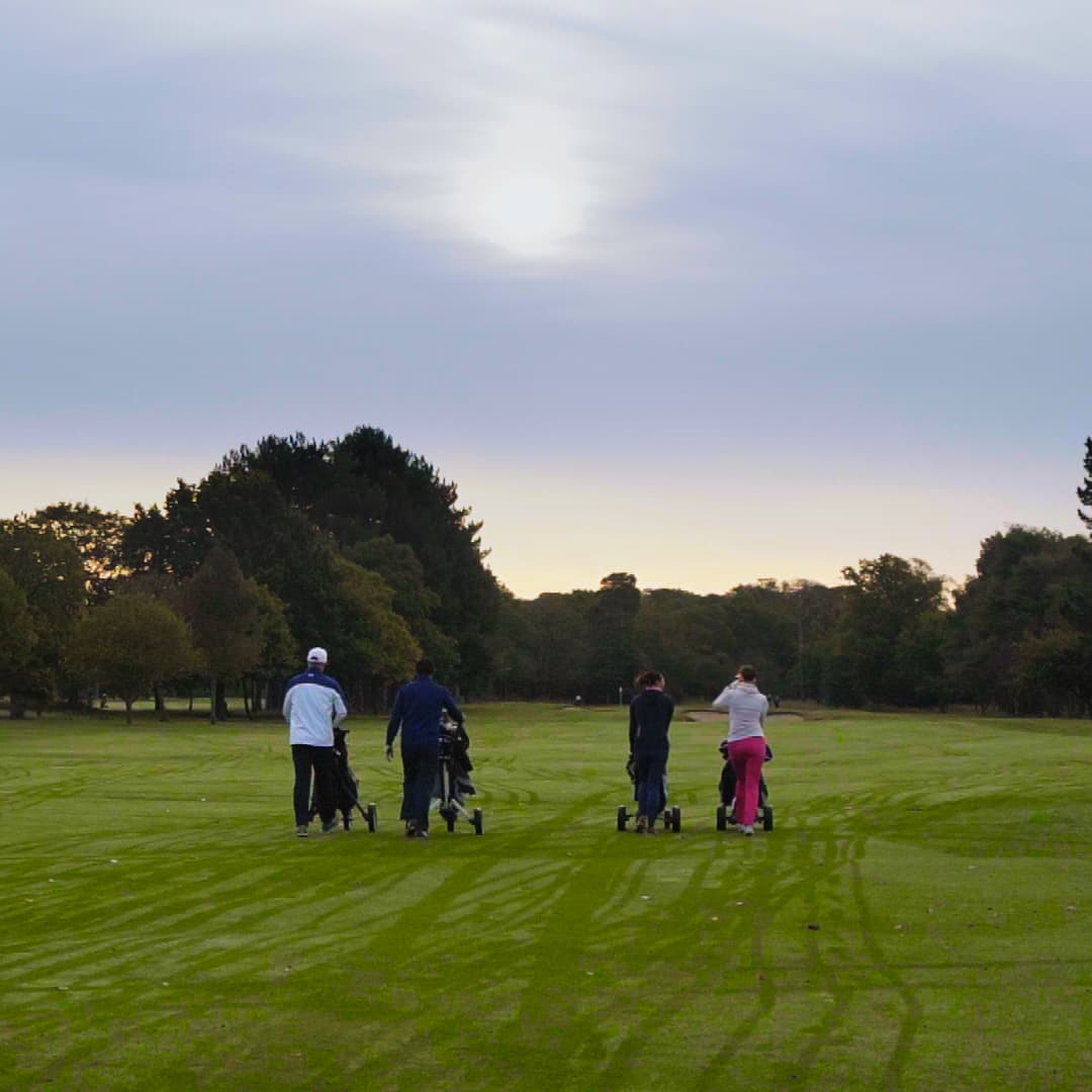Four society golfers walking together down an Ashford Manor fairway.