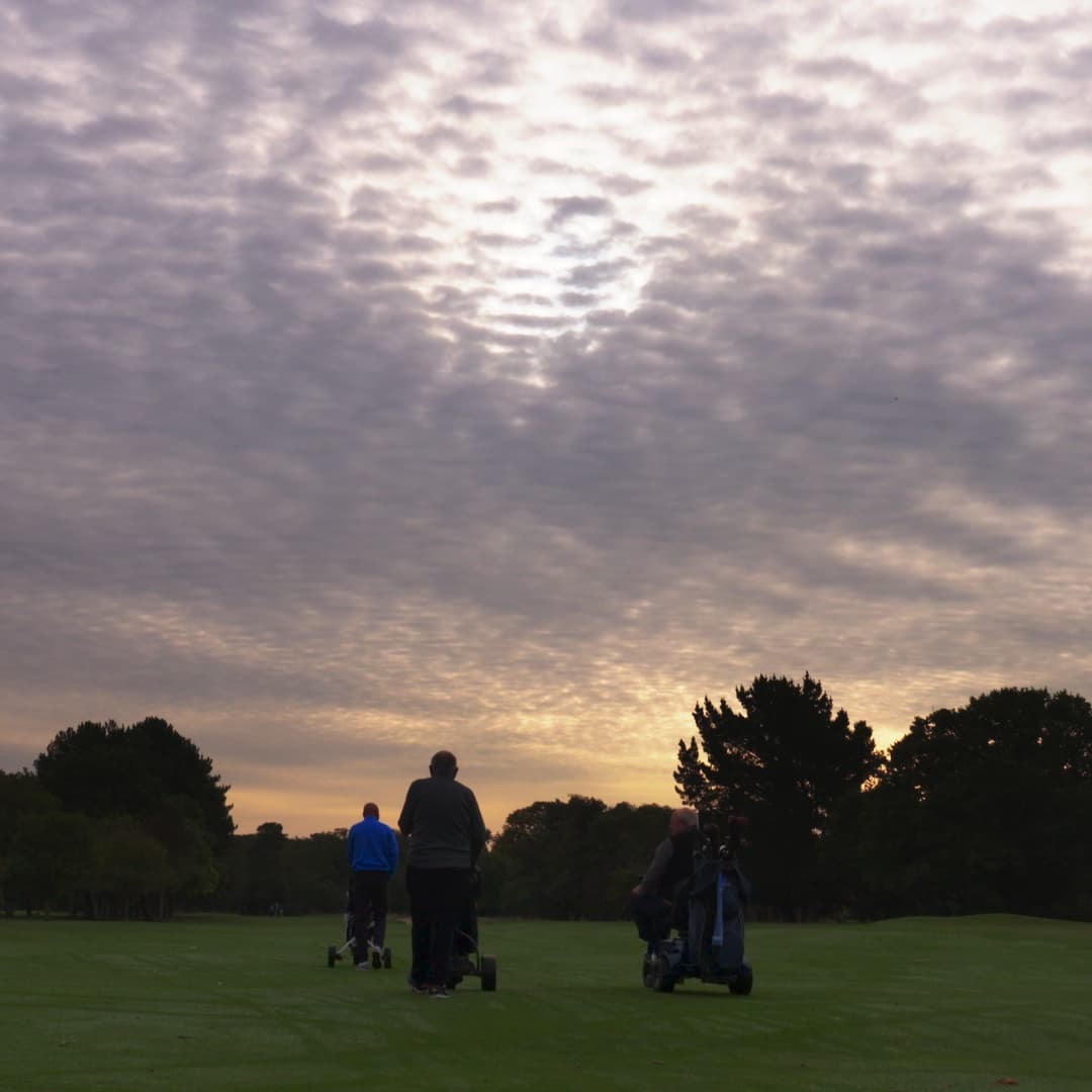 Society golfers walking the Ashford Manor course beneath a winter evening sky.