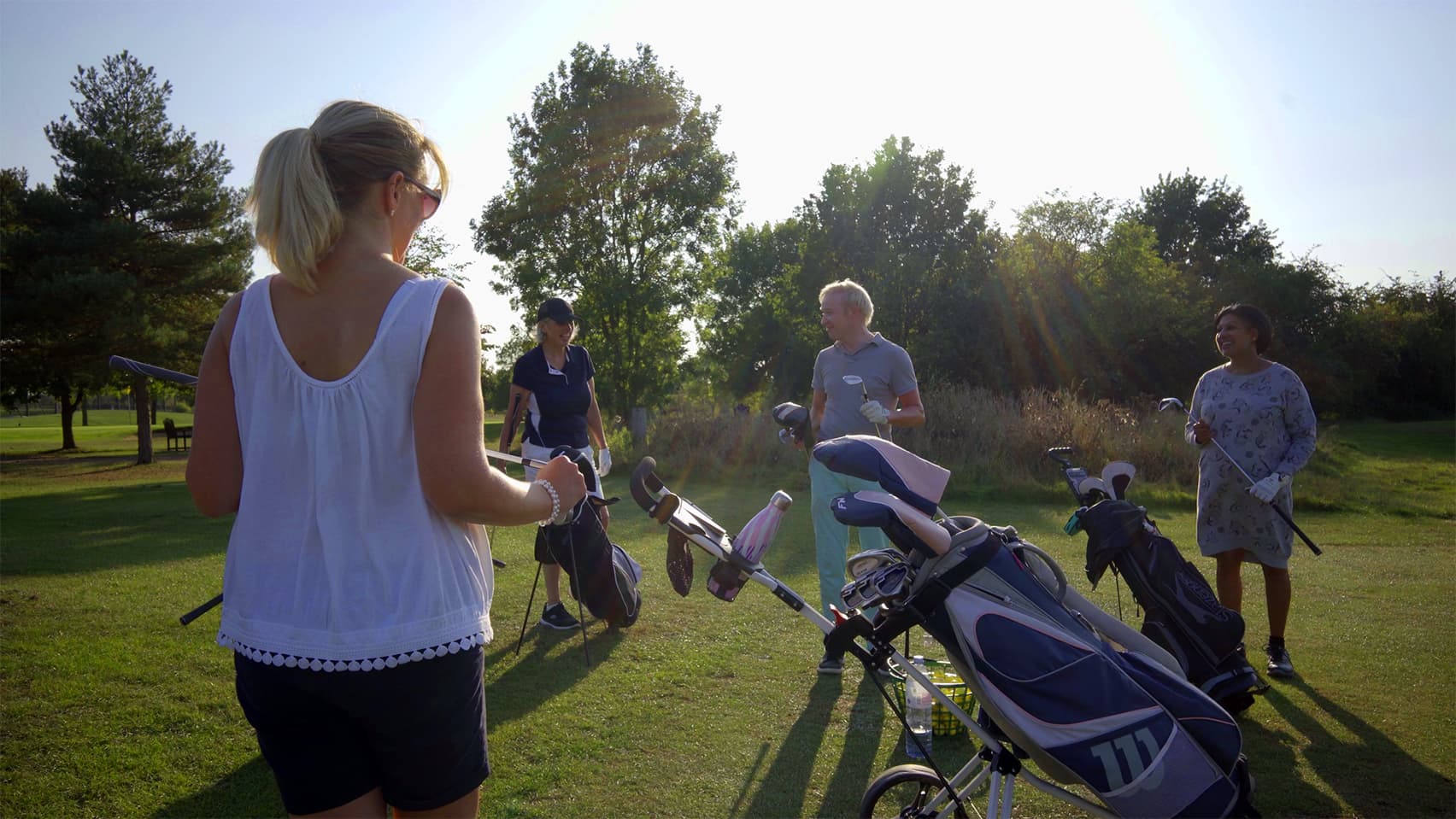 Four beginner golfers gather with their bags on the course at Horton Golf Park.