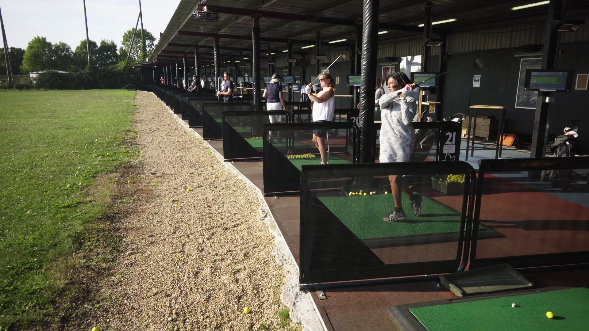 Golfers practising from adjacent driving-range bays at Horton Golf Park.