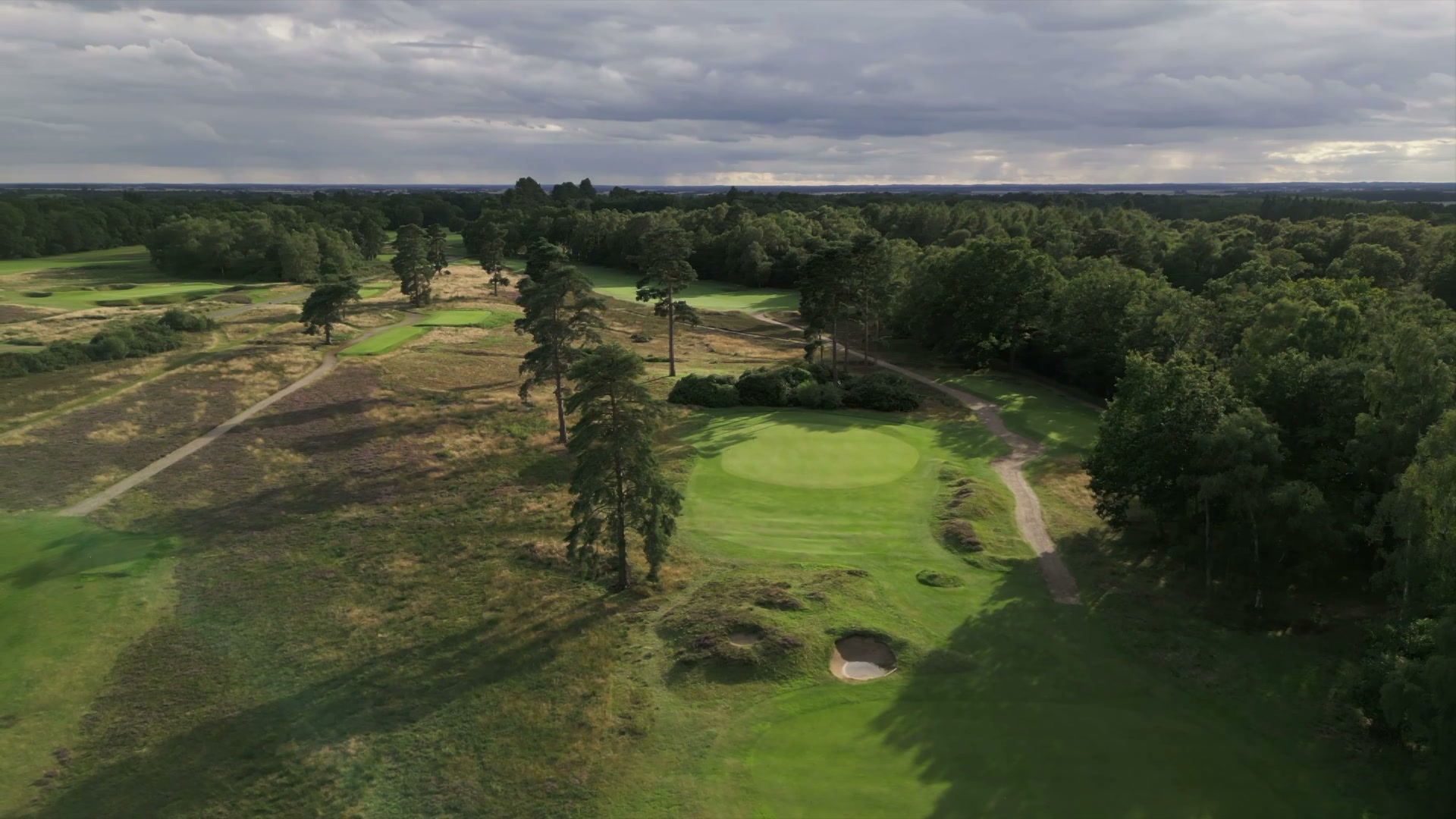 Sunlight breaking through trees across a Woodhall Spa green.
